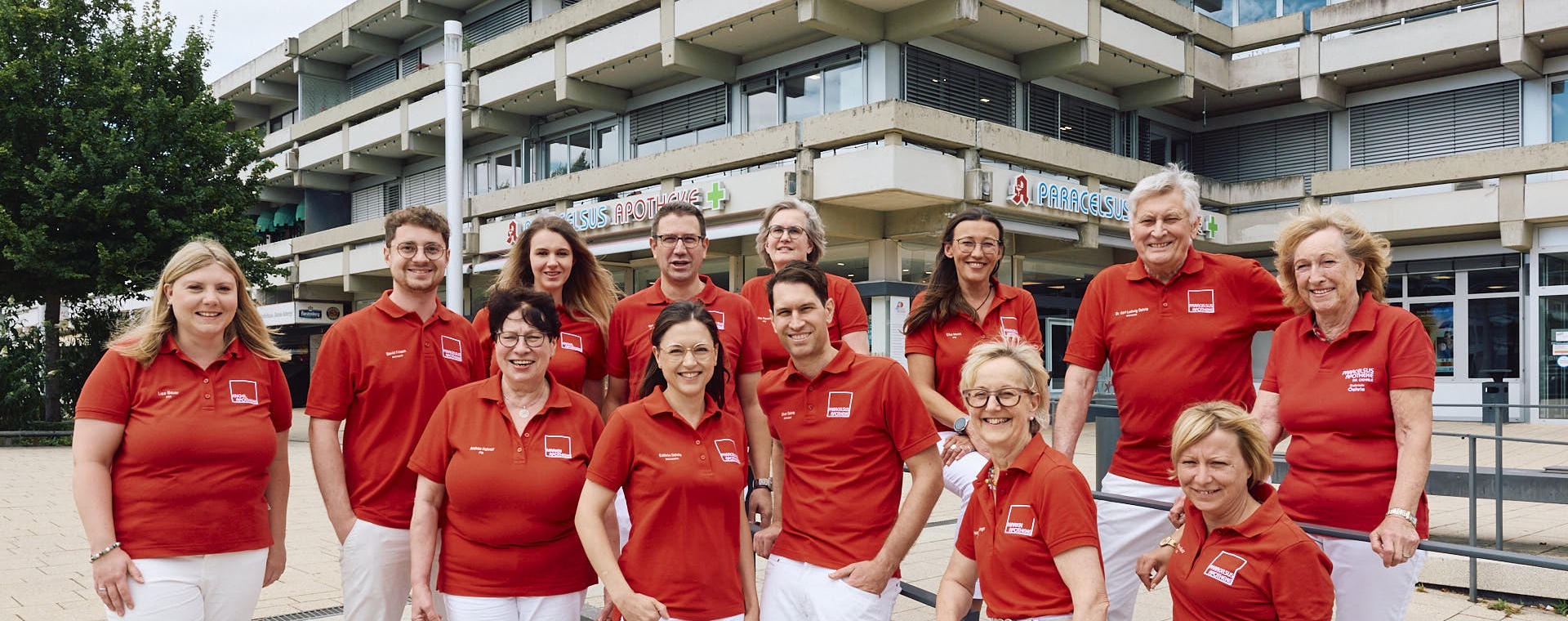 Gruppenbild der Mitarbeitenden der Marien Apothke in roten Shirts und weißen Hosen